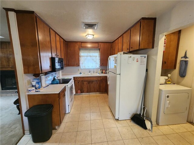 kitchen featuring white appliances, sink, a textured ceiling, light tile patterned flooring, and washer / dryer