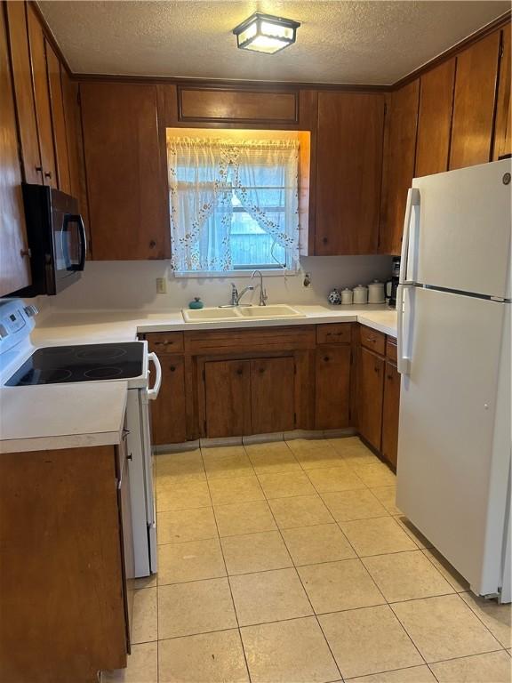 6026 Killarmet, Corpus Christi, TX 78413 - kitchen with white appliances, a sink, light countertops, a textured ceiling, and brown cabinets