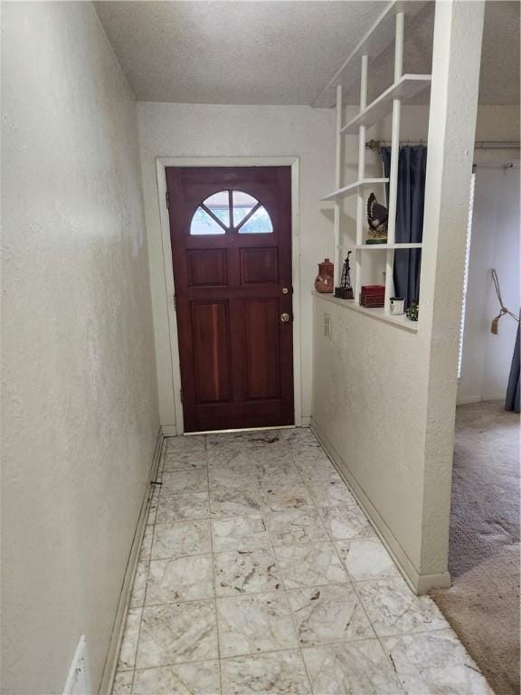 doorway with carpet floors and a textured ceiling