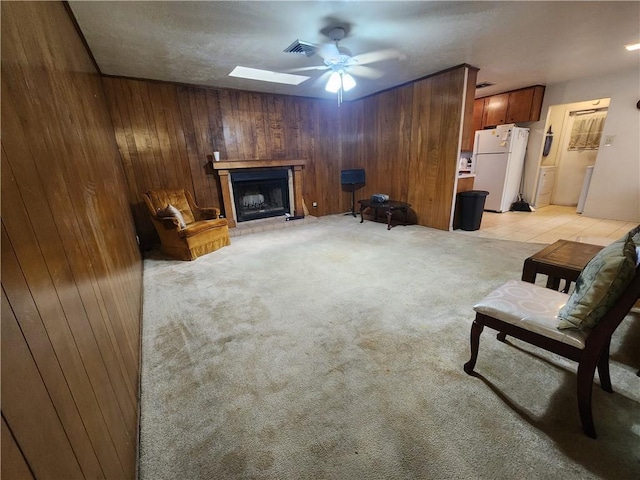 sitting room featuring light colored carpet, ceiling fan, and wooden walls