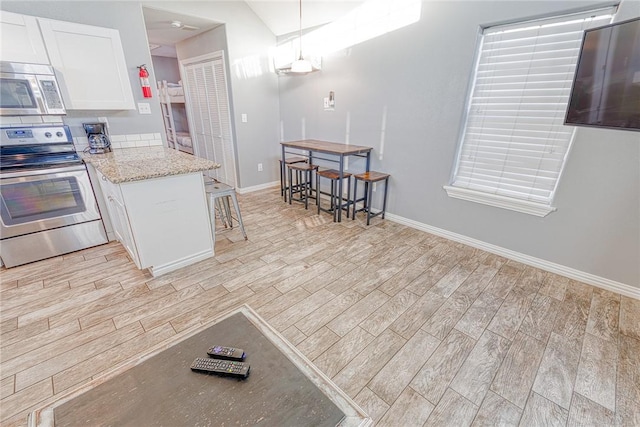4601 Gulfbreeze Blvd Unit 1, 2, 3, 4, 5, Corpus Christi, TX 78402 - kitchen featuring light stone countertops, pendant lighting, a kitchen bar, white cabinets, and appliances with stainless steel finishes