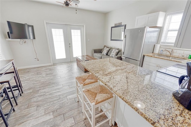 4601 Gulfbreeze Blvd Unit 1, 2, 3, 4, 5, Corpus Christi, TX 78402 - kitchen featuring french doors, white cabinets, a kitchen breakfast bar, stainless steel fridge, and light hardwood / wood-style floors