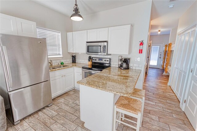 4601 Gulfbreeze Blvd Unit 1, 2, 3, 4, 5, Corpus Christi, TX 78402 - kitchen with kitchen peninsula, stainless steel appliances, sink, white cabinetry, and hanging light fixtures