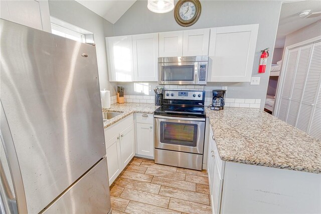 4601 Gulfbreeze Blvd Unit 1, 2, 3, 4, 5, Corpus Christi, TX 78402 - kitchen with kitchen peninsula, appliances with stainless steel finishes, tasteful backsplash, light stone counters, and white cabinetry