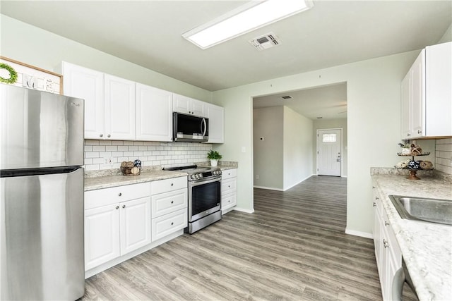 kitchen featuring stainless steel appliances, white cabinets, and light hardwood / wood-style flooring