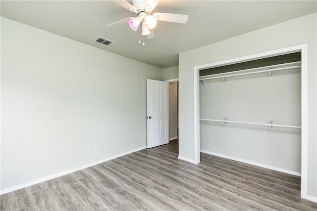 unfurnished bedroom with ceiling fan, wood-type flooring, and a closet