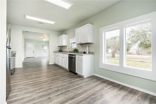 kitchen featuring white cabinetry, appliances with stainless steel finishes, light hardwood / wood-style floors, and decorative backsplash