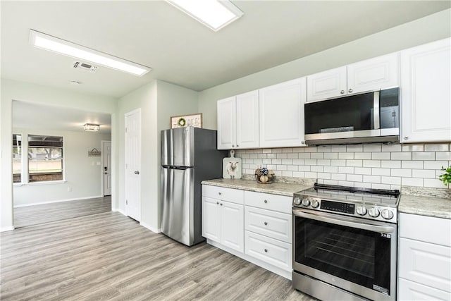 kitchen with white cabinetry, stainless steel appliances, light stone counters, tasteful backsplash, and light wood-type flooring