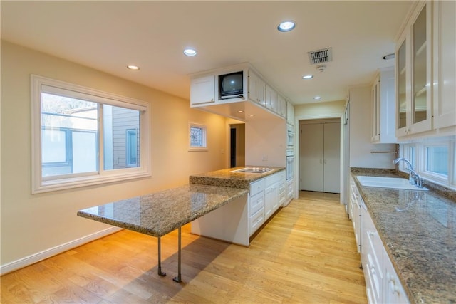 kitchen featuring white cabinetry, sink, and dark stone counters