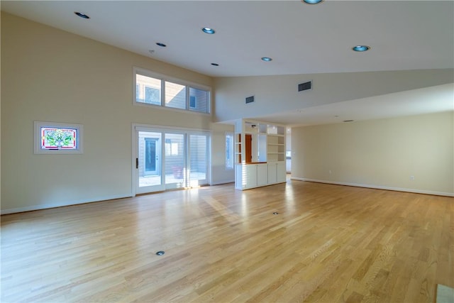 unfurnished living room featuring high vaulted ceiling and light wood-type flooring