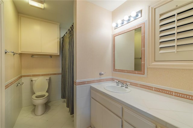 bathroom featuring tile patterned floors, vanity, toilet, and tile walls