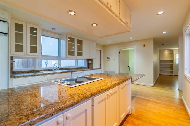 kitchen featuring dark stone countertops, sink, white electric stovetop, and white cabinets