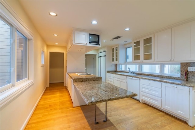 kitchen featuring white cabinetry, white dishwasher, sink, and light stone counters