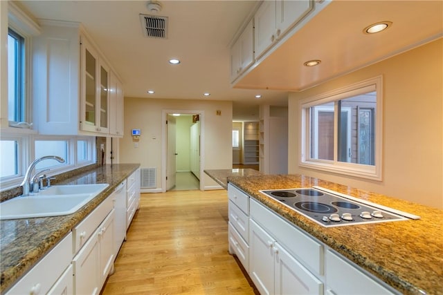 kitchen featuring electric stovetop, sink, white cabinets, and light hardwood / wood-style floors