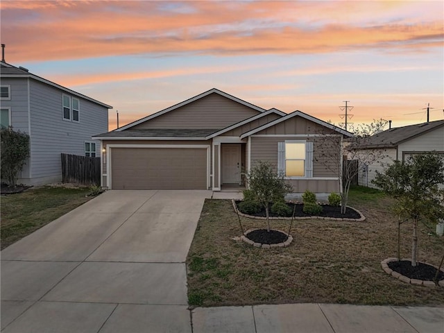 view of front of home with an attached garage, fence, driveway, a front lawn, and board and batten siding