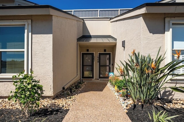 doorway to property with metal roof, a standing seam roof, and stucco siding