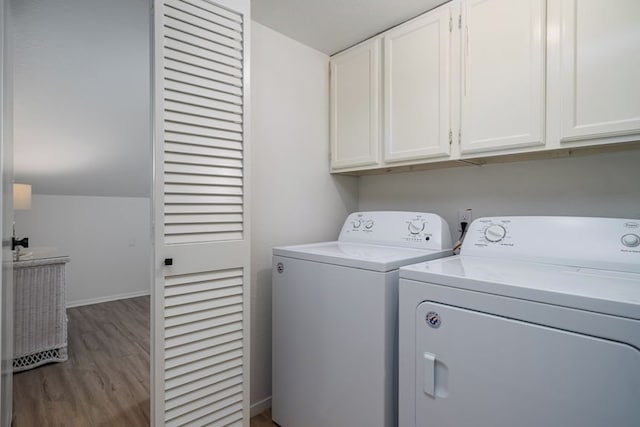 washroom with baseboards, washer and dryer, cabinet space, and wood finished floors