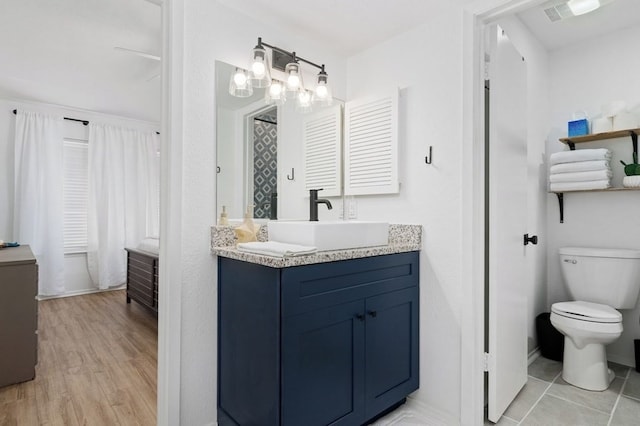 full bath with visible vents, baseboards, toilet, wood finished floors, and vanity