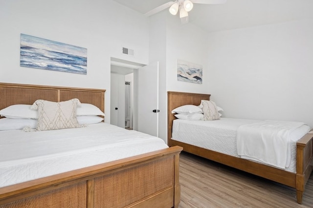 bedroom featuring visible vents, ceiling fan, light wood-style floors, and high vaulted ceiling