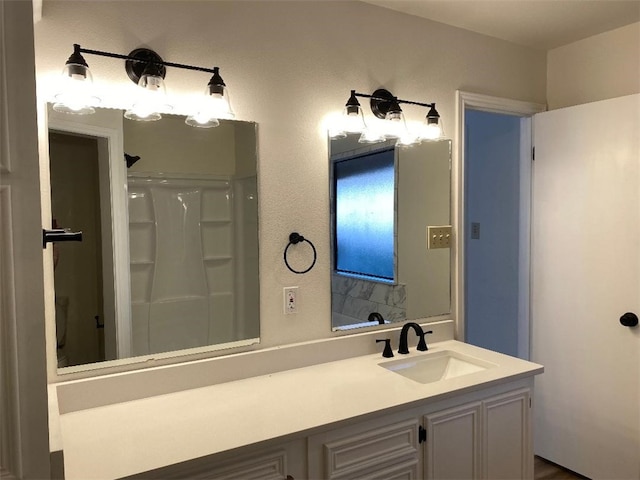 bathroom featuring walk in shower and vanity