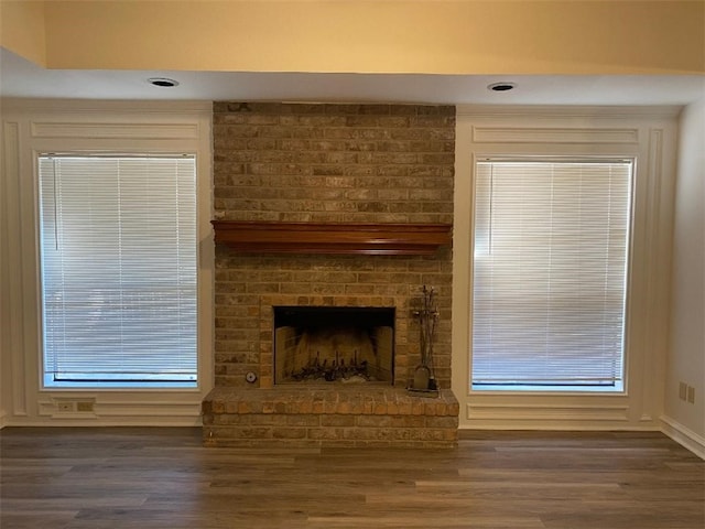 unfurnished living room with a fireplace, a wealth of natural light, and dark wood-type flooring