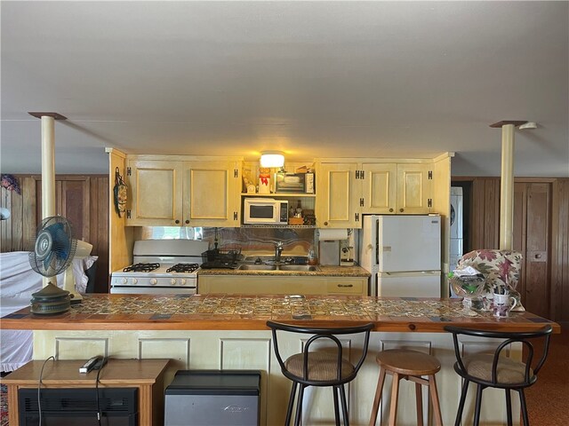 kitchen with a breakfast bar, sink, and white appliances