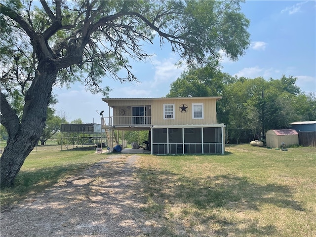 back of house with a sunroom, a storage unit, and a lawn