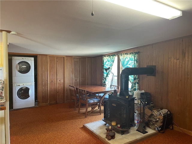 interior space featuring wood walls, a wood stove, and stacked washer and dryer