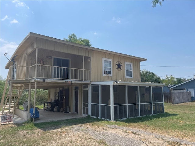 rear view of property featuring a lawn, a sunroom, and a patio