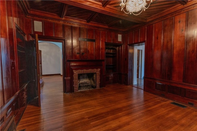 living room featuring visible vents, coffered ceiling, an inviting chandelier, wood walls, and crown molding