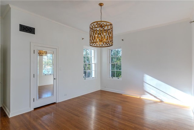 unfurnished room with visible vents, wood finished floors, an inviting chandelier, crown molding, and baseboards