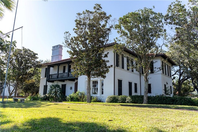 mediterranean / spanish-style house with a tiled roof, a front lawn, a balcony, and stucco siding