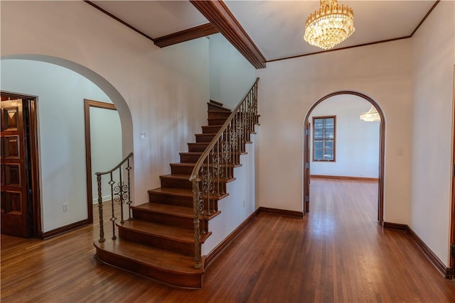 stairs featuring arched walkways, wood finished floors, and ornamental molding