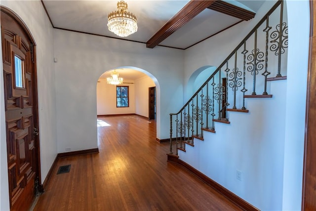 foyer entrance with wood finished floors, visible vents, arched walkways, stairs, and a notable chandelier