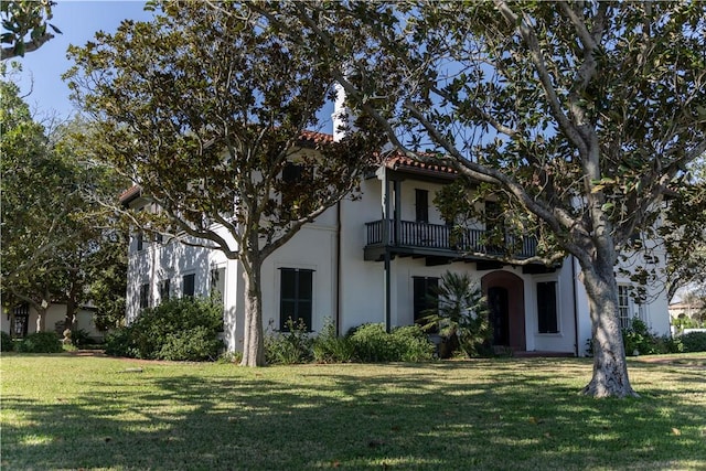 mediterranean / spanish-style home featuring a tiled roof, a front yard, a balcony, and stucco siding