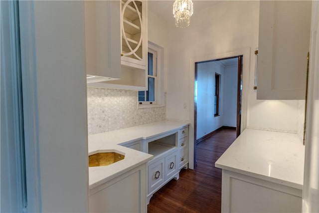 kitchen featuring a notable chandelier, light stone counters, decorative light fixtures, tasteful backsplash, and dark wood-style flooring