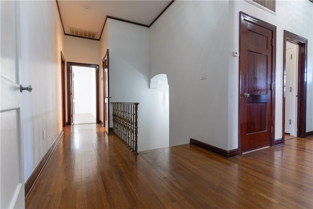 corridor with visible vents, wood finished floors, arched walkways, and baseboards