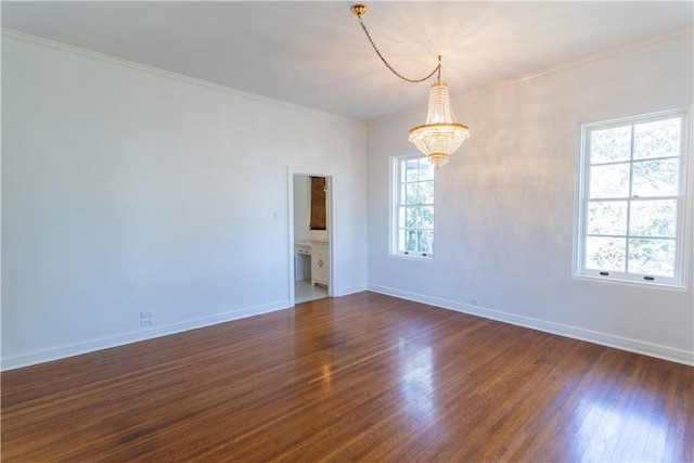 empty room featuring dark wood finished floors, baseboards, crown molding, and an inviting chandelier