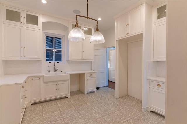 kitchen with recessed lighting, white cabinetry, glass insert cabinets, and a sink