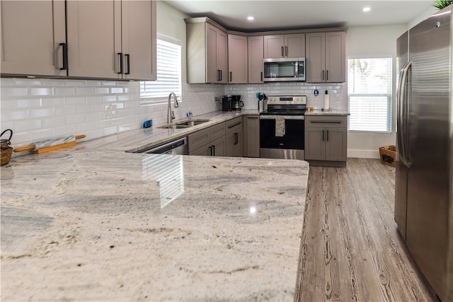 kitchen with stainless steel appliances, a wealth of natural light, and light stone counters