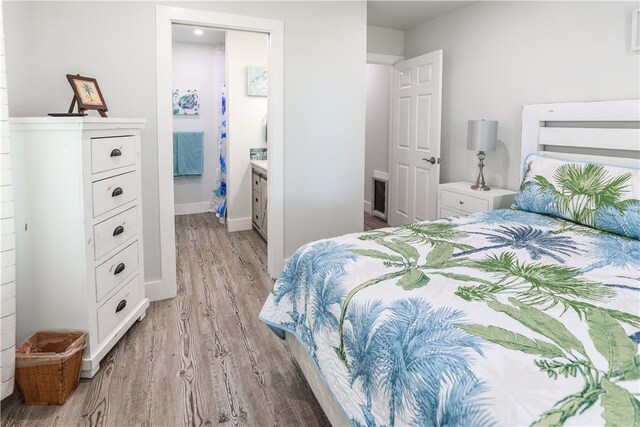 bedroom featuring ensuite bathroom and light hardwood / wood-style floors