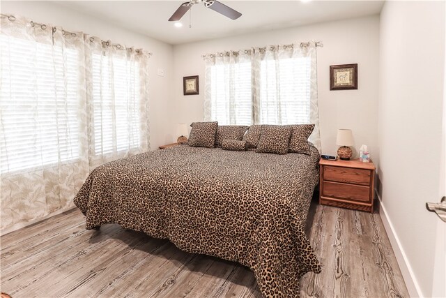 bedroom featuring light wood-type flooring, multiple windows, and ceiling fan