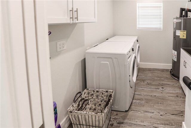 laundry area featuring cabinets, independent washer and dryer, electric water heater, and light hardwood / wood-style floors