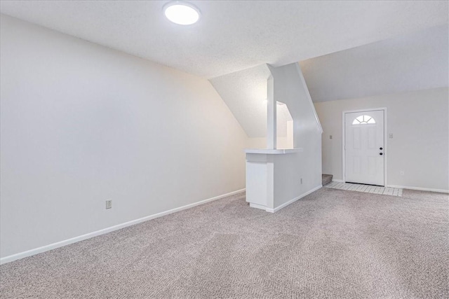 bonus room featuring lofted ceiling, baseboards, a textured ceiling, and light colored carpet