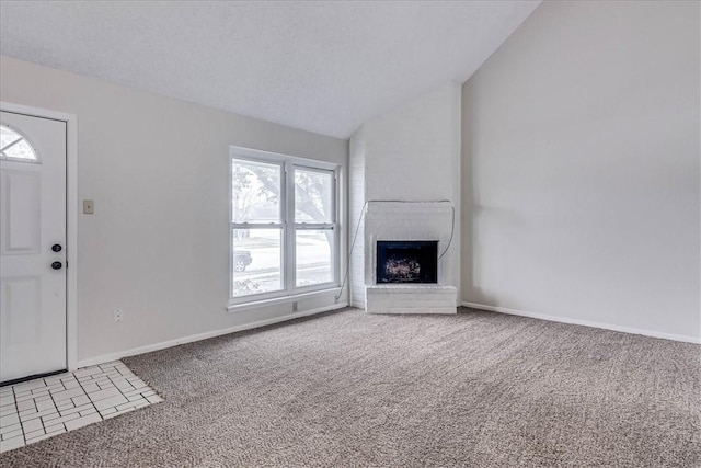 unfurnished living room featuring lofted ceiling, a textured ceiling, light colored carpet, baseboards, and a brick fireplace