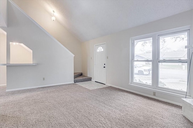 entrance foyer featuring baseboards, light colored carpet, stairway, vaulted ceiling, and a textured ceiling