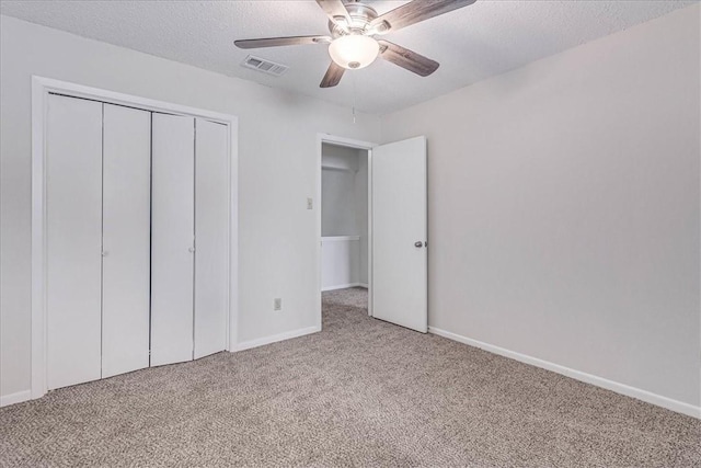 unfurnished bedroom with a textured ceiling, a closet, carpet flooring, and visible vents