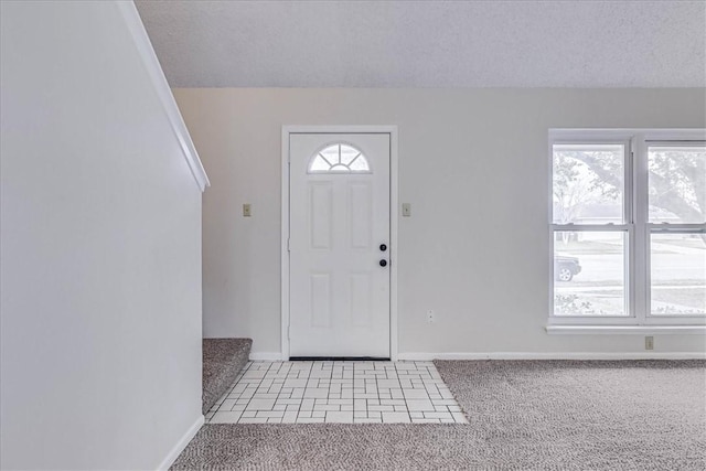 entrance foyer with light carpet, baseboards, a textured ceiling, and light tile patterned flooring