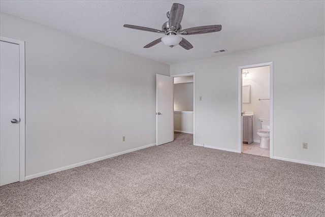 unfurnished bedroom with a textured ceiling, light carpet, visible vents, baseboards, and ensuite bath