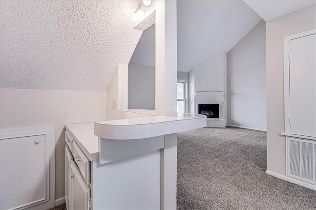 bathroom featuring baseboards, visible vents, lofted ceiling, a textured ceiling, and a fireplace